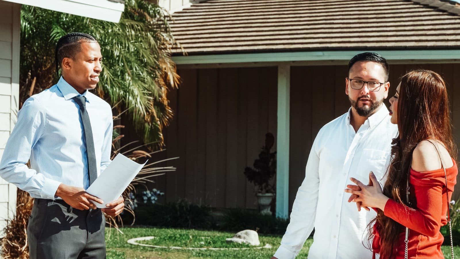 A buyer discussing a home with their agent outside a house
