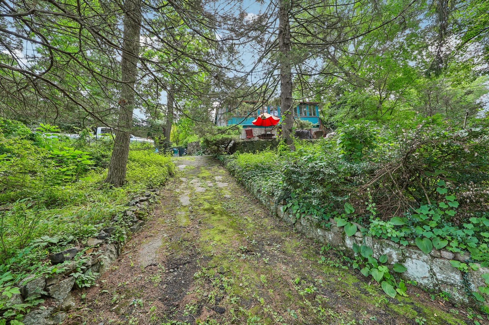 Wooded driveway lined with stone walls leading up to the lot