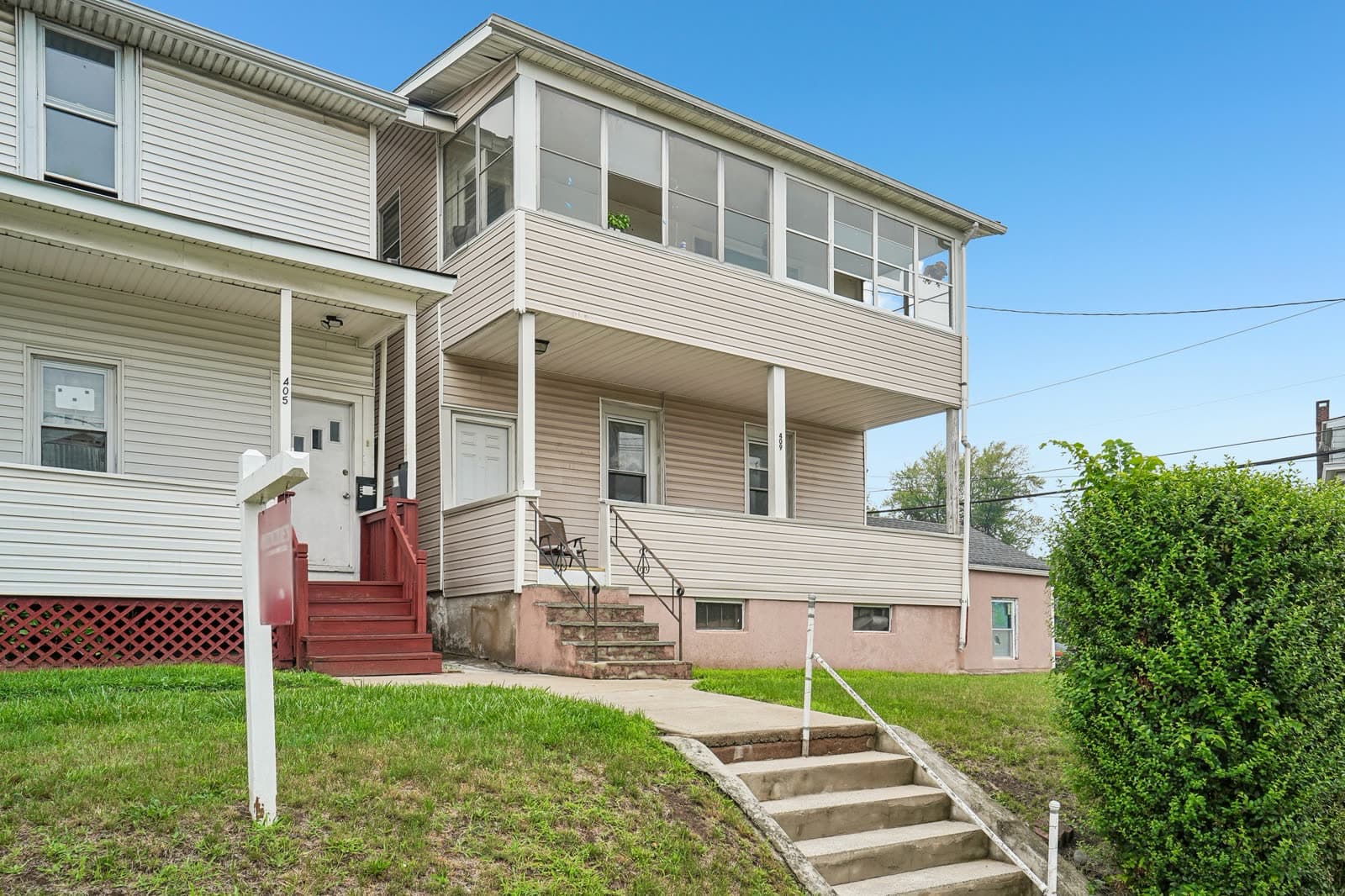 Front of the two-family home with a first-floor porch and an enclosed second-floor sunporch