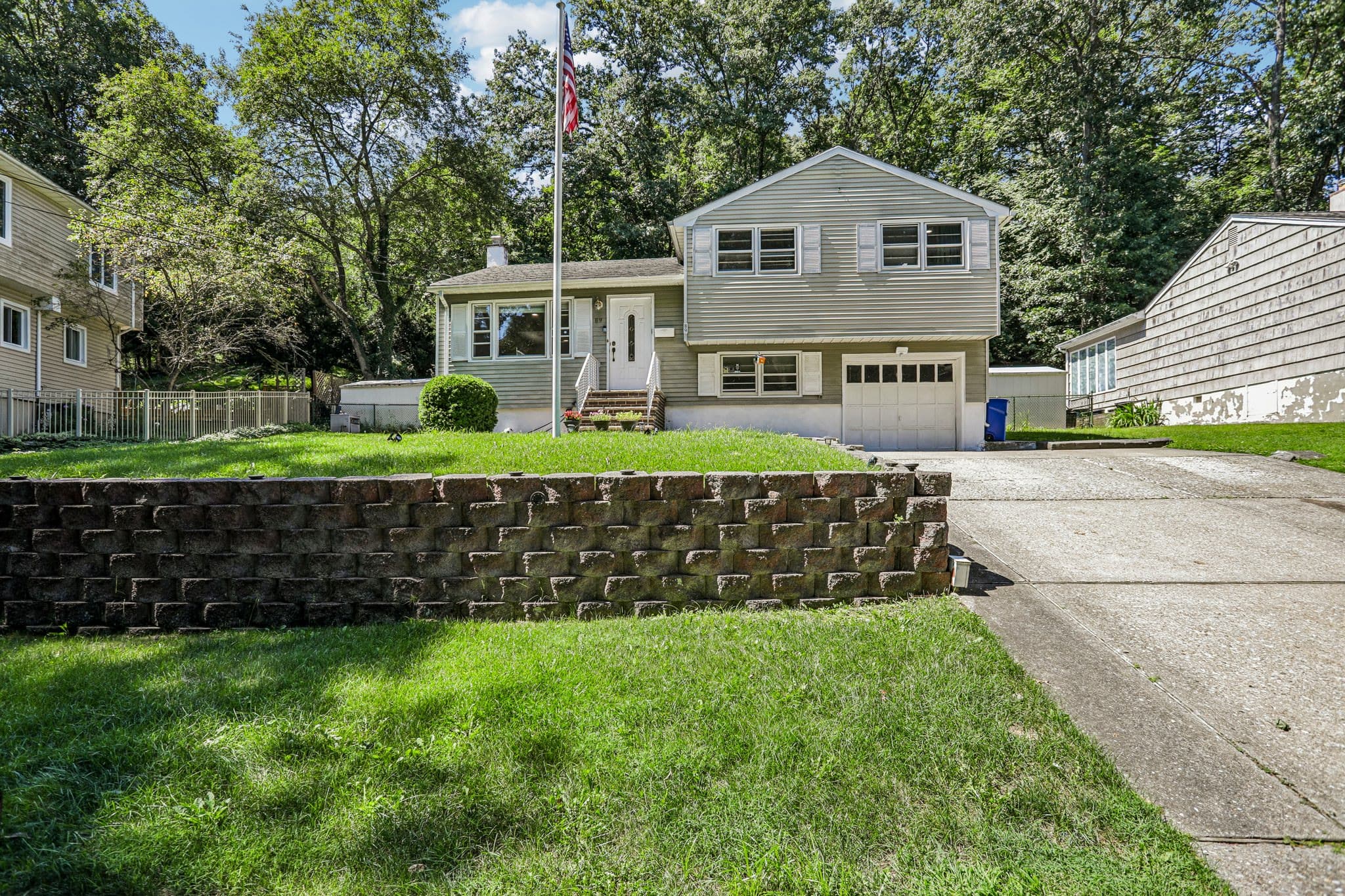 Split-level home with a stone retaining wall and front lawn in Bloomingdale, New Jersey